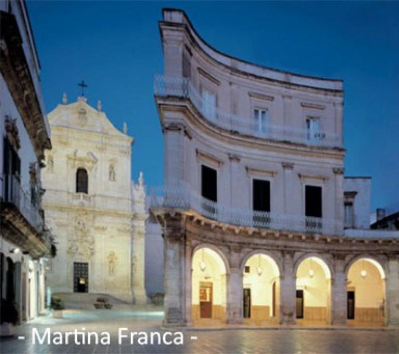 Piazza con architettura barocca e chiesa a Martina Franca, illuminata al tramonto.